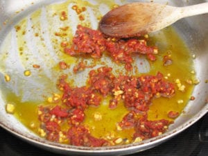 Cooking anchovies, tomato paste and garlic