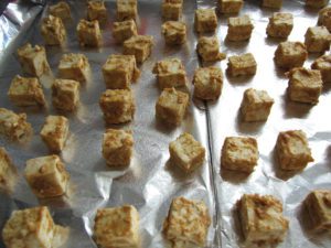 Coated tofu cubes on a baking sheet sprayed with nonstick