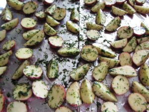 Potatoes tossed in olive oil, salt, pepper, fresh dill and garlic powder ready to roast